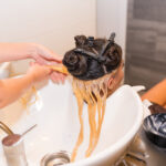 Hairdresser cleaning the head with hot water and soap to a brunette client in the beauty salon
